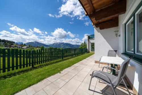 a patio with a table and chairs and a fence at Aparthotel Sunrise in Ramsau am Dachstein
