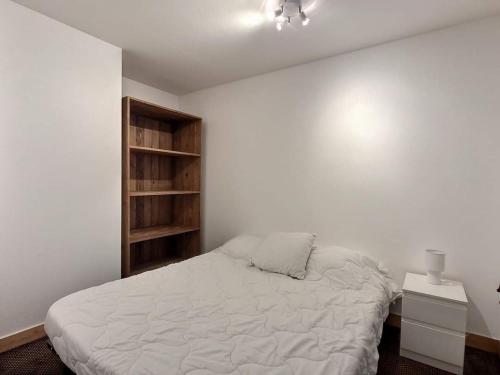- une chambre blanche avec un lit et une étagère dans l'établissement Superbe appartement avec piscine au centre St lary village, à Saint-Lary-Soulan