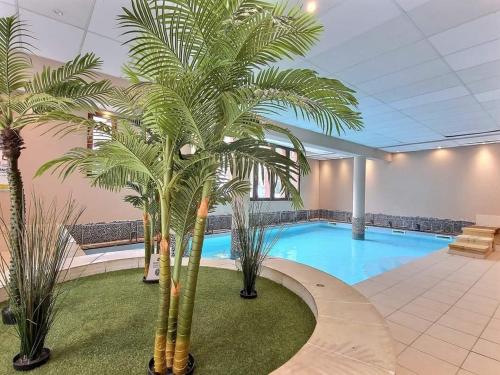 une grande piscine avec des palmiers dans un bâtiment dans l'établissement Superbe appartement avec piscine au centre St lary village, à Saint-Lary-Soulan