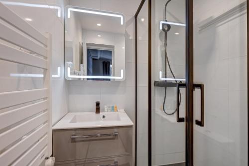 une salle de bain avec un lavabo et un miroir dans l'établissement Paris Marais Luxueux Studio pour 2 personnes, à Paris