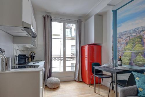Il comprend une cuisine équipée d'un réfrigérateur rouge et d'une table avec des chaises. dans l'établissement Paris Marais Luxueux Studio pour 2 personnes, à Paris