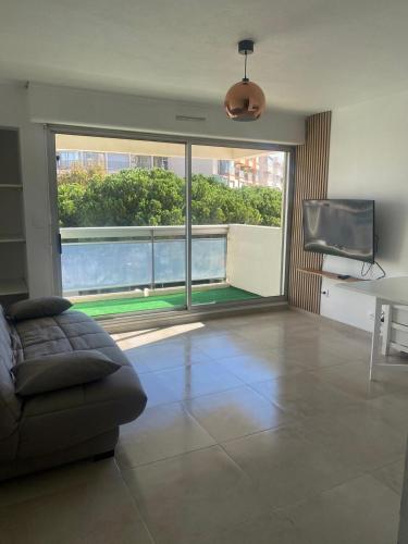 un salon avec un canapé et une grande fenêtre dans l'établissement Magnifique Studio, à Mauguio
