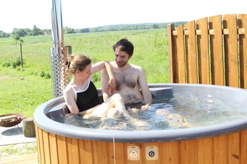 a man and a woman sitting in a hot tub at Enghytten in Stenum