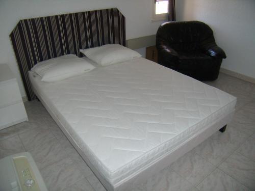 a large white bed in a room with a chair at Stephanie Immobilier in Saintes-Maries-de-la-Mer
