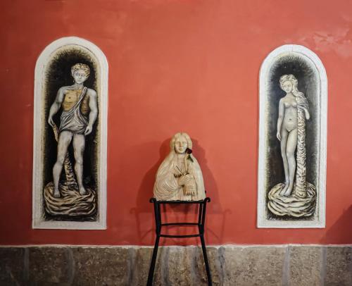 three statues on the side of a wall with a chair at Menhir Rooms in Campobasso