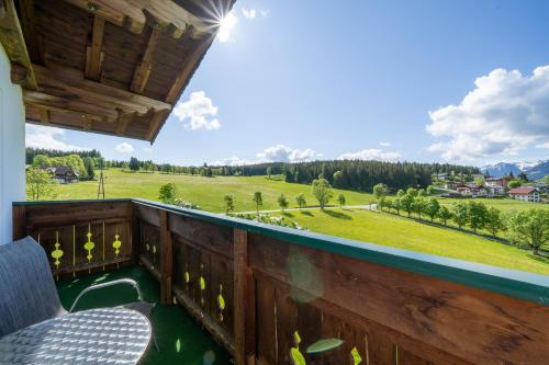 a balcony with a view of a green field and mountains at Aparthotel Sunrise in Ramsau am Dachstein