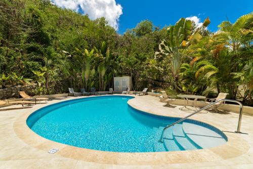 a swimming pool in a resort with chairs and trees at Golden Acre Beach Villa-2 mins walk - Alleynes Bay in Saint James
