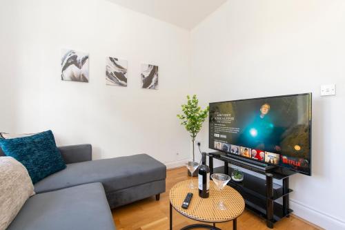 a living room with a couch and a flat screen tv at Ealing Gem 3 Bath, 2 En-Suite Flat with Parking in Ealing