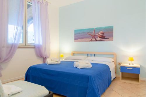 una camera con due letti con lenzuola blu e una finestra di Appartamenti 34 Spiaggia di Pescoluse a Marina di Pescoluse