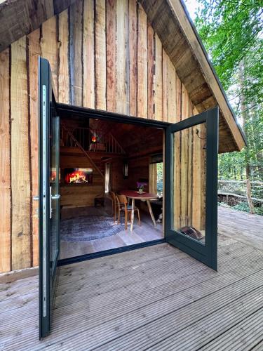 an open door of a wooden house with a table at New Unique Treehouses with hot tub in Oisterwijk in Oisterwijk