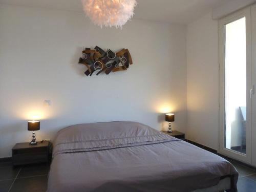 ein Schlafzimmer mit einem Bett, zwei Lampen und einem Kronleuchter in der Unterkunft Appartement vue mer - 2ch 2sdb - Parking - Vue splendide mer et montagne in Calvi