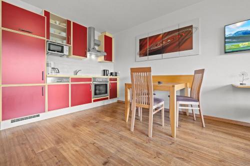 a kitchen with red cabinets and a table and chairs at Aparthotel Sunrise in Ramsau am Dachstein