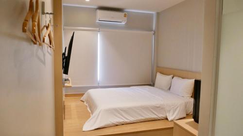 a small bedroom with a bed with white sheets at The Staytion Hotel at Sukhumvit in Amphoe Phra Khanong