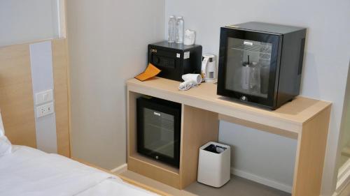 a room with a tv and a microwave on a table at The Staytion Hotel at Sukhumvit in Amphoe Phra Khanong