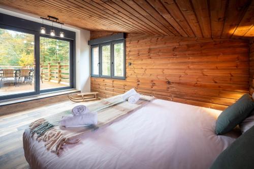 una camera da letto con un letto grande in una parete di legno di Chalet La Perle Verte, luxe, piscine, spa et sauna a Gérardmer