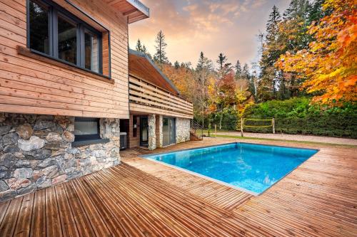 une piscine sur une terrasse à côté d'une maison dans l'établissement Chalet La Perle Verte, luxe, piscine, spa et sauna, à Gérardmer