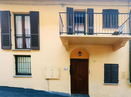 a building with black shuttered windows and a door at Casa vacanze Re Cit Diano d'Alba in Diano dʼAlba
