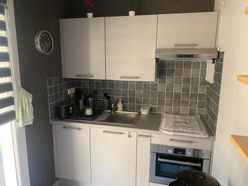 une cuisine avec des armoires blanches et un évier dans l'établissement Les Bisquines, à Saint-Malo