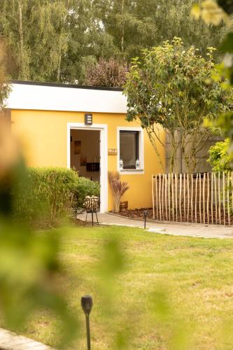 a yellow house with a fence in a yard at Alivio - Thuiskomen bij jezelf op vakantie in Lummen