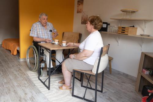 a woman sitting at a table with a man in a wheelchair at Alivio - Thuiskomen bij jezelf op vakantie in Lummen