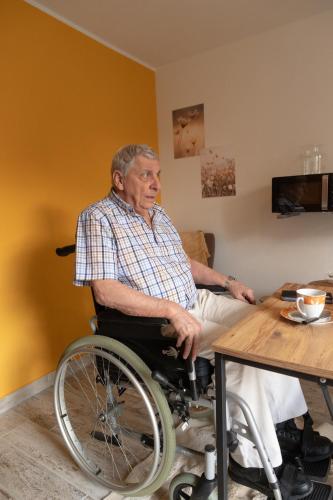 an older man in a wheelchair sitting at a table at Alivio - Thuiskomen bij jezelf op vakantie in Lummen