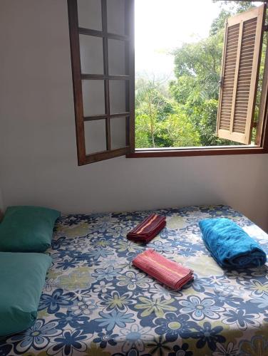 a bed with pillows on it in a room with a window at Casa Mar e Montanha 1, Vista para o Mar in Trindade