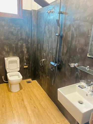 a bathroom with a shower and a toilet and a sink at Orana Villa in Ahangama