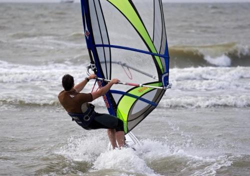 a man is holding onto a sail in the ocean at Ruime en Zonnige 5 sterren Vakantiewoning SVN7tien in Doornhoek
