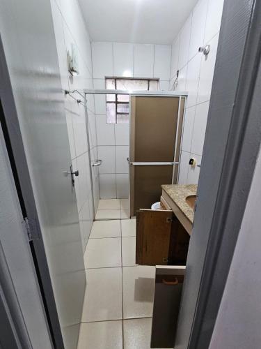 a white bathroom with a shower and a sink at CIG Hostel in Goiânia