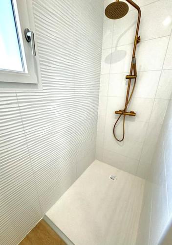 une salle de bain avec une douche avec pommeau de douche dans l'établissement Les Gites des jardins d'Oscar l'Appartement, à La Faye