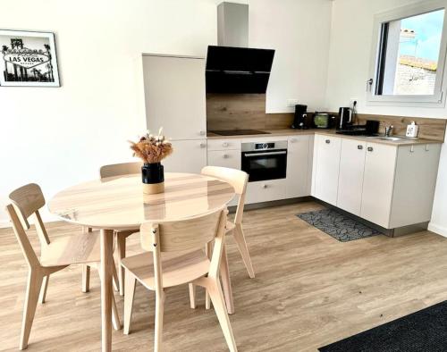 une cuisine avec une table et des chaises dans une pièce dans l'établissement Les Gites des jardins d'Oscar l'Appartement, à La Faye