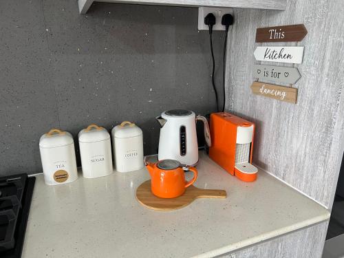 an orange coffee cup sitting on a counter with appliances at Seascape Modern Accomodation Near CLUB MED ALBION in Albion