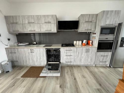 a kitchen with wooden cabinets and an open dishwasher at Seascape Modern Accomodation Near CLUB MED ALBION in Albion