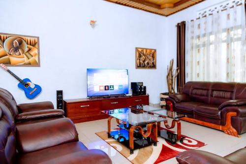 a living room with leather furniture and a flat screen tv at HIde Flowers Residence in Gasanze