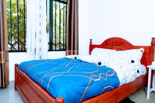 a bedroom with a bed with a blue comforter at HIde Flowers Residence in Gasanze