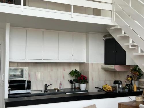 une cuisine avec des armoires blanches, un évier et un micro-ondes dans l'établissement Un duplex de charme à Paris, à Paris