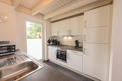 a kitchen with white cabinets and a sink at Lee - Nordhorn in Nordhorn