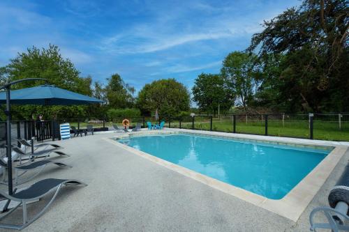 une piscine avec des chaises et un parasol dans l'établissement La Ferme, à Lardanva