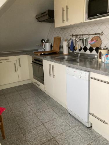 a kitchen with white cabinets and a sink at Gästewohnung 25 in Wildeshausen