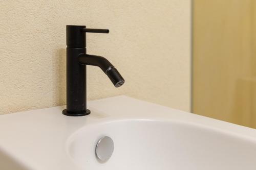 a black faucet on top of a white sink at Fiorentini 22 - Suite Luxury con SPA in Matera