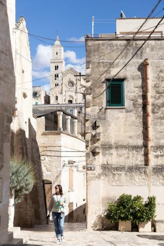a woman walking down a street in front of a building at Fiorentini 22 - Suite Luxury con SPA in Matera