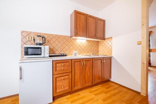 a kitchen with wooden cabinets and a white refrigerator at Apartmány Iwona in Rokytnice nad Jizerou