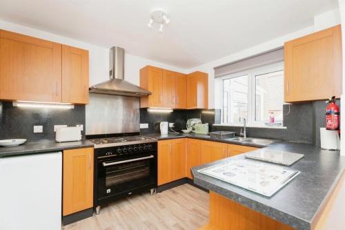 a kitchen with wooden cabinets and a stove top oven at SeaCross Sheringham Norfolk Coast 4beds, sleeps 7 in Sheringham