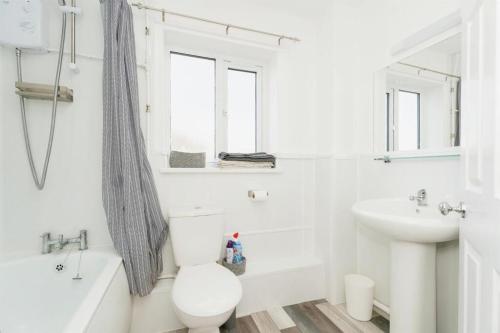 a white bathroom with a toilet and a sink at SeaCross Sheringham Norfolk Coast 4beds, sleeps 7 in Sheringham