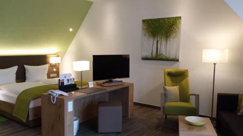 a hotel room with a bed and a desk with a television at Hotel-Restaurant Pfälzer Hof in Edenkoben