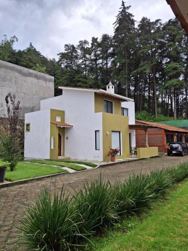 a white and yellow house on the side of a road at Las casas de las flores in Ibarra