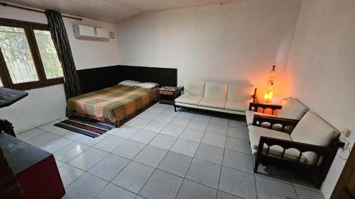 a bedroom with a bed and a couch and a chair at Kurupy in Puerto Iguazú