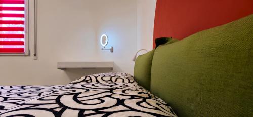 a bedroom with a bed with green pillows and a window at Casa Sunrise - The Guest House in Sciacca