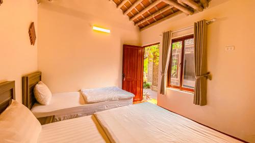two beds in a room with a window at Tuan Nam Homestay in Ninh Binh