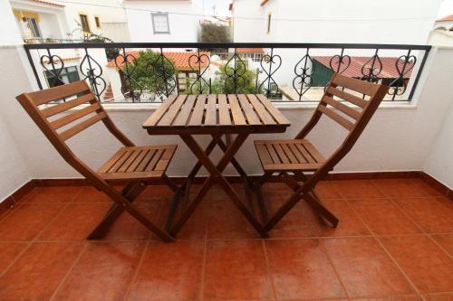 a wooden table and two chairs on a balcony at Quarto Tulipa in Vila Nova de Milfontes